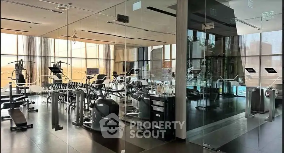 Luxurious gym with modern equipment and glass walls in upscale residential building.