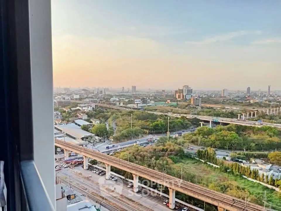 Stunning cityscape view from high-rise apartment window at sunset, showcasing urban landscape and greenery.
