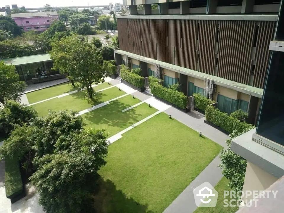 Lush green garden space in a modern residential complex, showcasing manicured lawns and contemporary architecture for serene urban living.