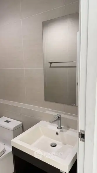 Modern bathroom with sleek sink and mirror in contemporary apartment.