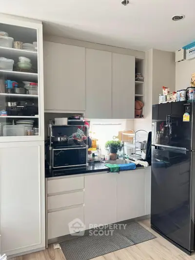Modern kitchen with sleek cabinets and black appliances, featuring a compact yet functional design.