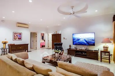 Spacious living room with modern decor and large TV, perfect for relaxation.