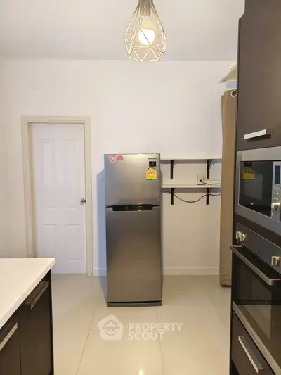 Modern kitchen with sleek appliances and minimalist design, featuring a stainless steel fridge and built-in oven.