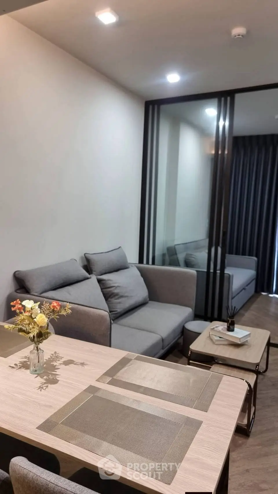 Modern living room with stylish gray sofa and elegant dining table setup