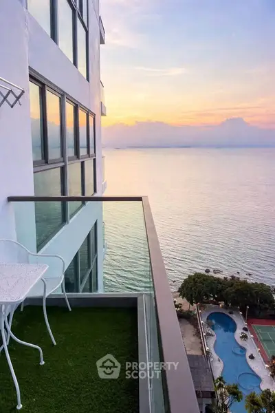 Stunning ocean view from modern balcony with glass railing and outdoor seating.