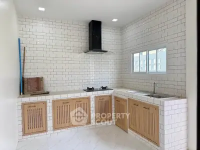 Modern kitchen with wooden cabinets and gas stove in a bright, tiled space.