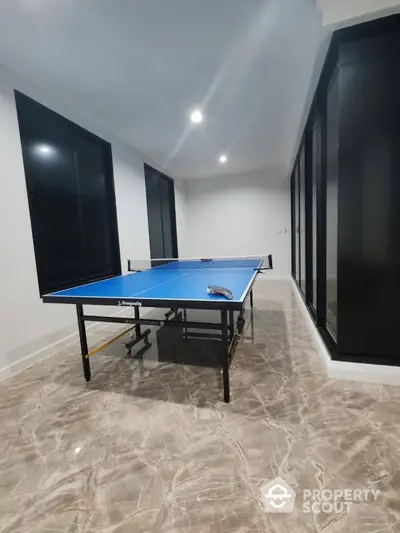 Spacious indoor recreation room with sleek marble flooring and ping pong table.