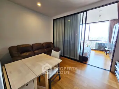 Modern apartment with open living room and bedroom, featuring a large balcony with city view.
