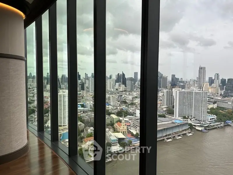 Stunning cityscape view from high-rise building with floor-to-ceiling windows overlooking river.
