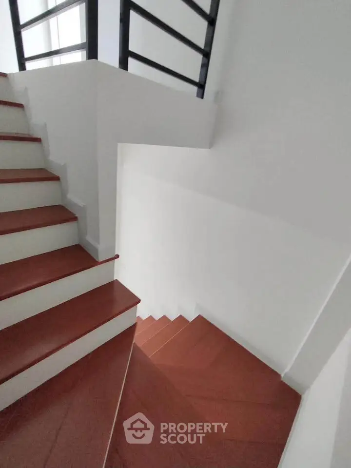 Modern staircase with sleek design and red steps in a contemporary building.
