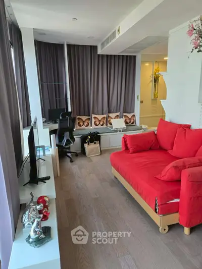 Modern living room with red sofa, TV, and stylish decor in a bright apartment.