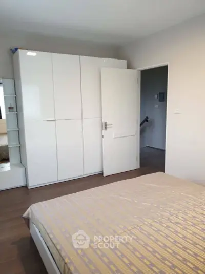 Spacious bedroom with modern white wardrobe and cozy bed in a stylish apartment.