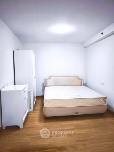 Spacious bedroom with minimalist design and wooden flooring