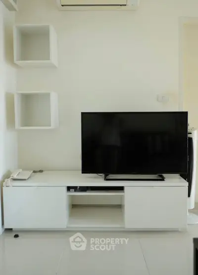 Modern living room with sleek white TV stand and mounted shelves, perfect for minimalist decor.