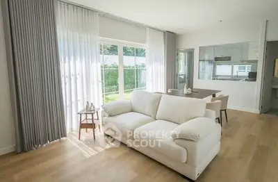 Bright and spacious living room with modern decor and large windows overlooking a lush garden.