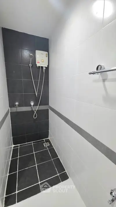 Modern minimalist bathroom with sleek black and white tiles and a wall-mounted water heater.