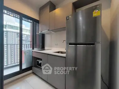 Modern kitchen with sleek appliances and balcony view in urban apartment.