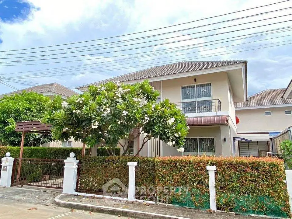 Charming two-story house with lush garden and gated entrance in a serene neighborhood.