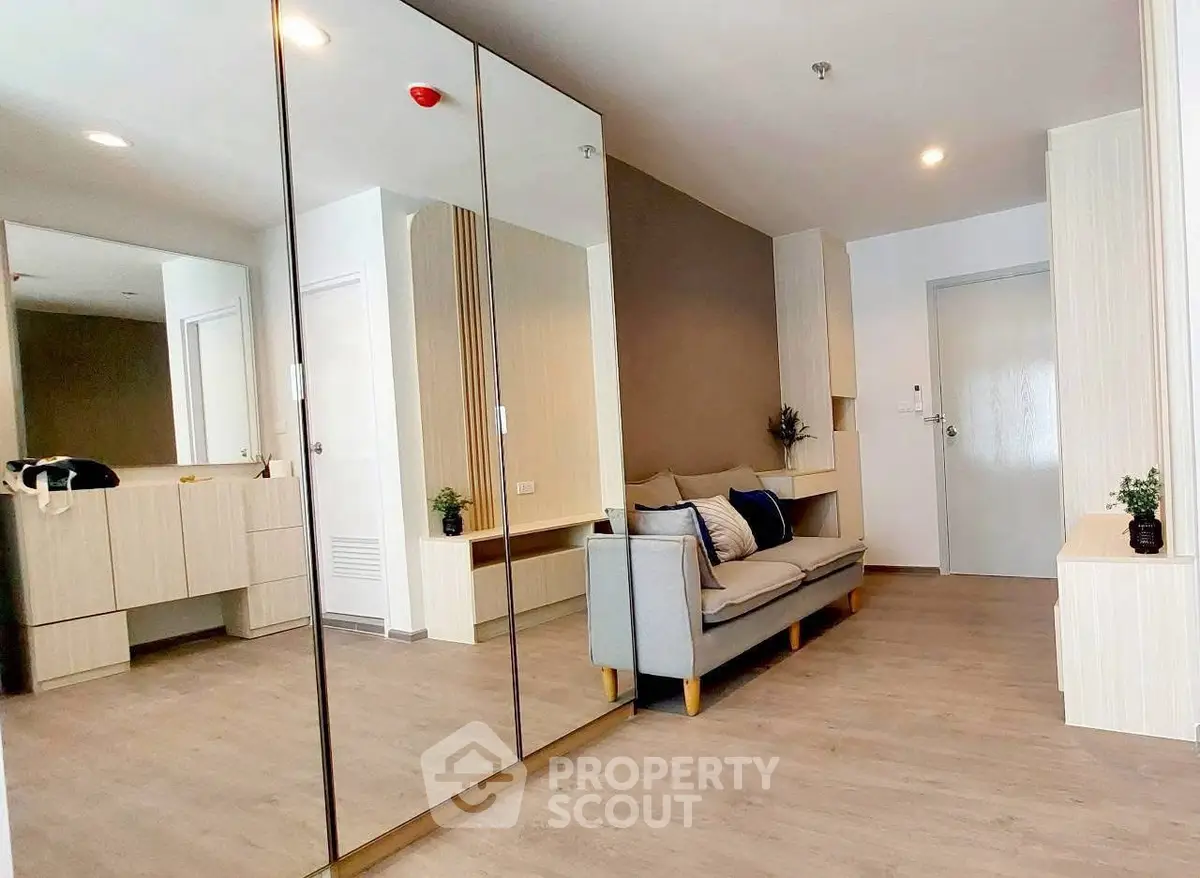 Modern living room with mirrored wardrobe and cozy sofa in stylish apartment.