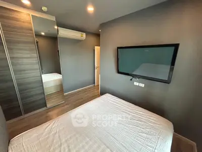 Modern bedroom with sleek design, featuring a wall-mounted TV and mirrored wardrobe.