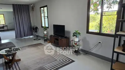 Spacious living room with modern decor and large windows offering natural light and garden views.