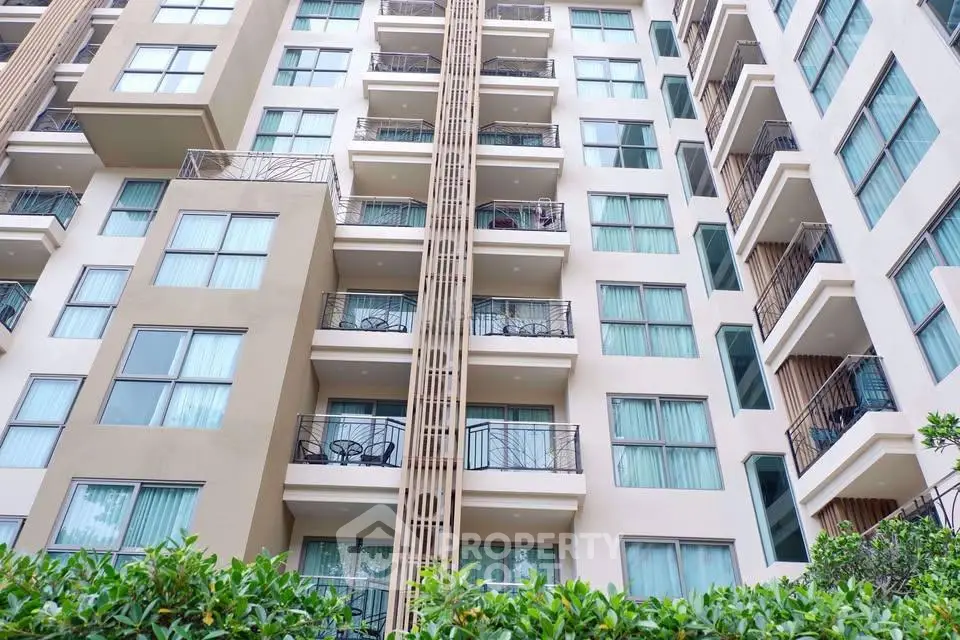 Modern multi-story apartment building with balconies and large windows, surrounded by greenery.