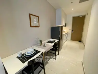 Modern kitchen with sleek design, featuring a compact dining area and stainless steel appliances.