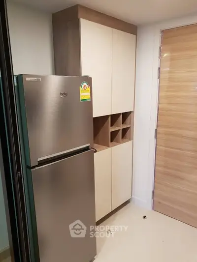 Modern kitchen with sleek fridge and stylish cabinetry in a contemporary apartment.