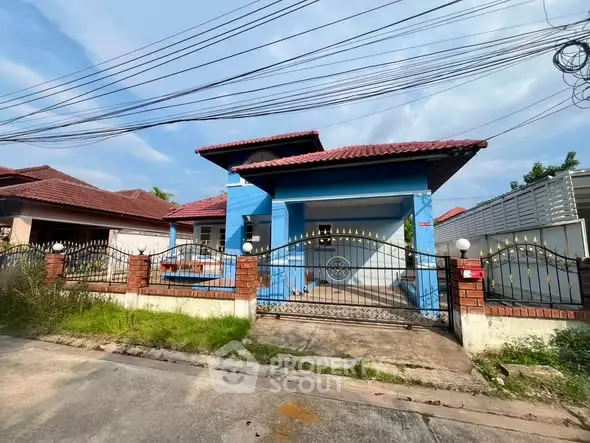 Charming blue single-family home with red roof and gated entrance in a serene neighborhood.