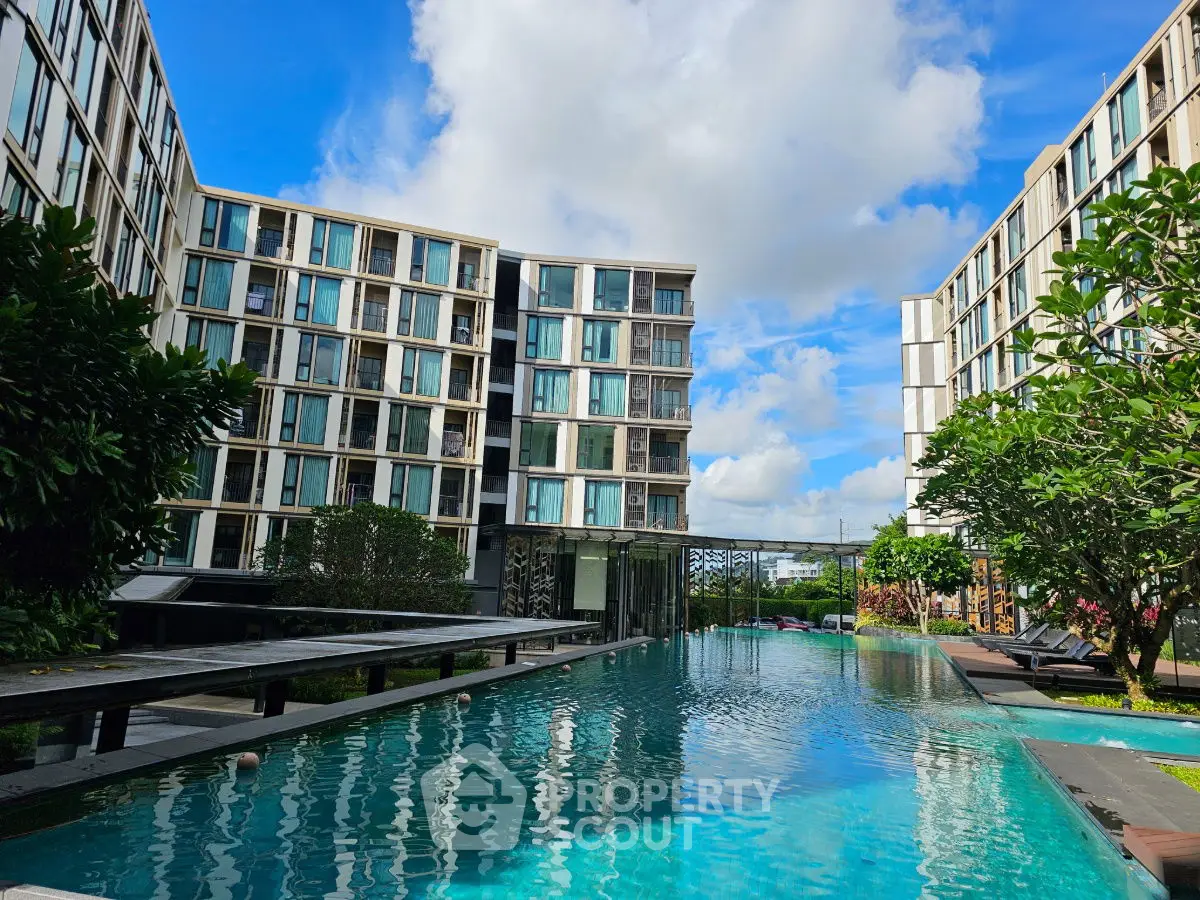 Luxurious modern apartment complex with stunning pool and lush greenery.
