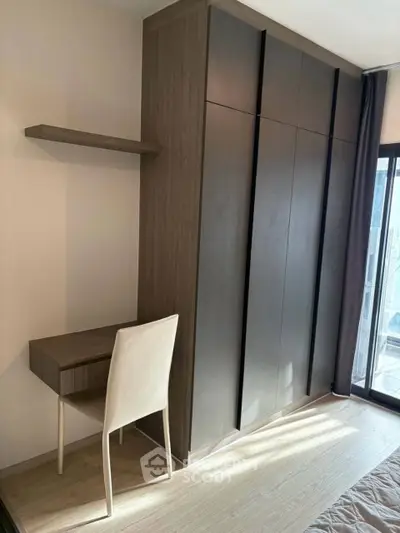 Modern bedroom with sleek wardrobe and minimalist desk, featuring floor-to-ceiling windows for natural light.