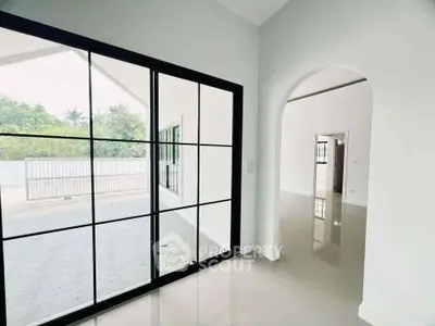 Spacious modern interior with large windows and glossy floors, offering a seamless indoor-outdoor transition.