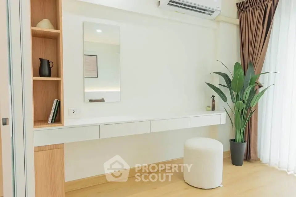 Modern minimalist interior with floating desk, stool, and potted plant by a window.