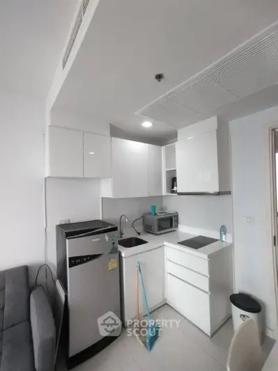 Modern compact kitchen with sleek white cabinets and stainless steel appliances
