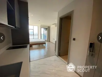 Spacious and modern apartment interior with sleek kitchen cabinets, gleaming marble floors, and abundant natural light from large windows leading to a cozy balcony.