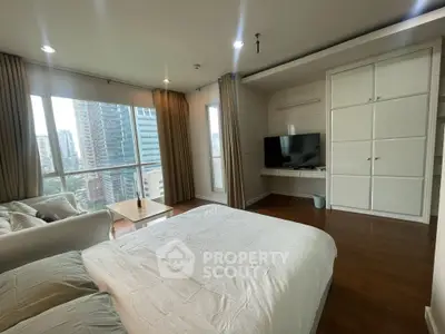 Spacious bedroom with city view, featuring modern decor and large windows for natural light.
