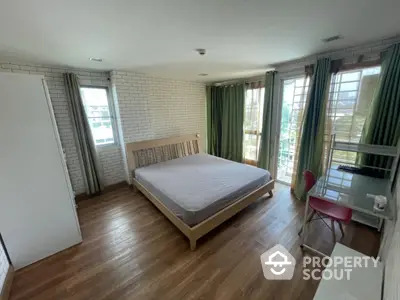 Spacious bedroom with large windows and modern furnishings in a stylish apartment.