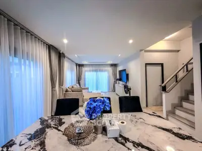 Elegant living room with marble dining table and cozy seating area, featuring modern decor and ample natural light.