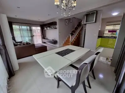 Spacious modern living and dining area with elegant chandelier and open kitchen layout.