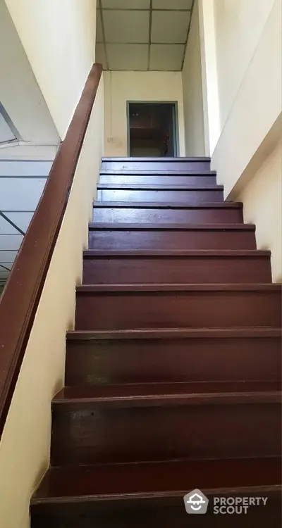 Classic wooden staircase leading to a bright upper level, showcasing the well-maintained interior of a charming property.