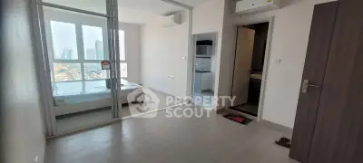 Modern apartment with bedroom, kitchenette, and city view, featuring sleek design and ample natural light.