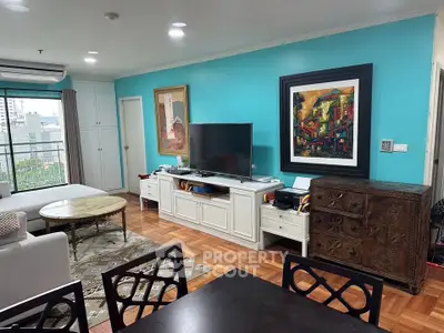 Spacious living room with vibrant decor and city view, featuring elegant furniture and artwork.