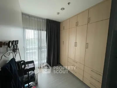 Spacious bedroom with large built-in wardrobe and natural light from window.