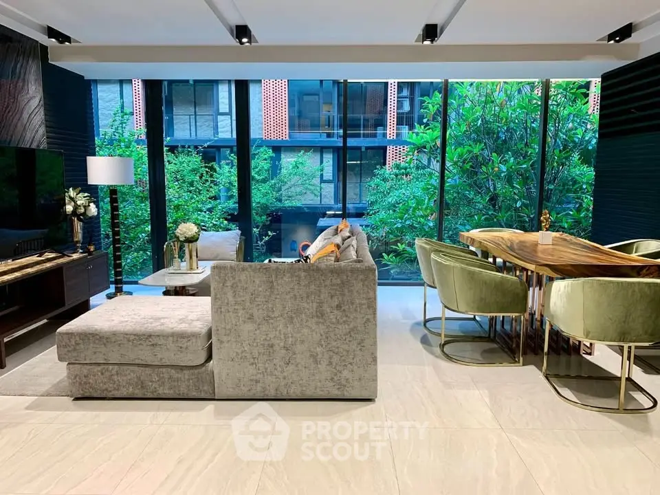 Luxurious modern living room with large windows and elegant dining area overlooking lush greenery.
