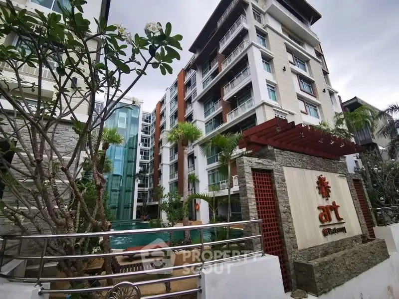 Modern condominium exterior with pool and lush landscaping in urban setting.