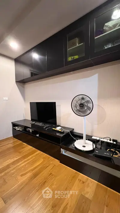 Modern living room with sleek black entertainment unit and wooden flooring