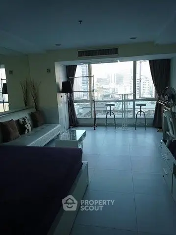 Spacious modern living room with large windows offering stunning city views and stylish furnishings.