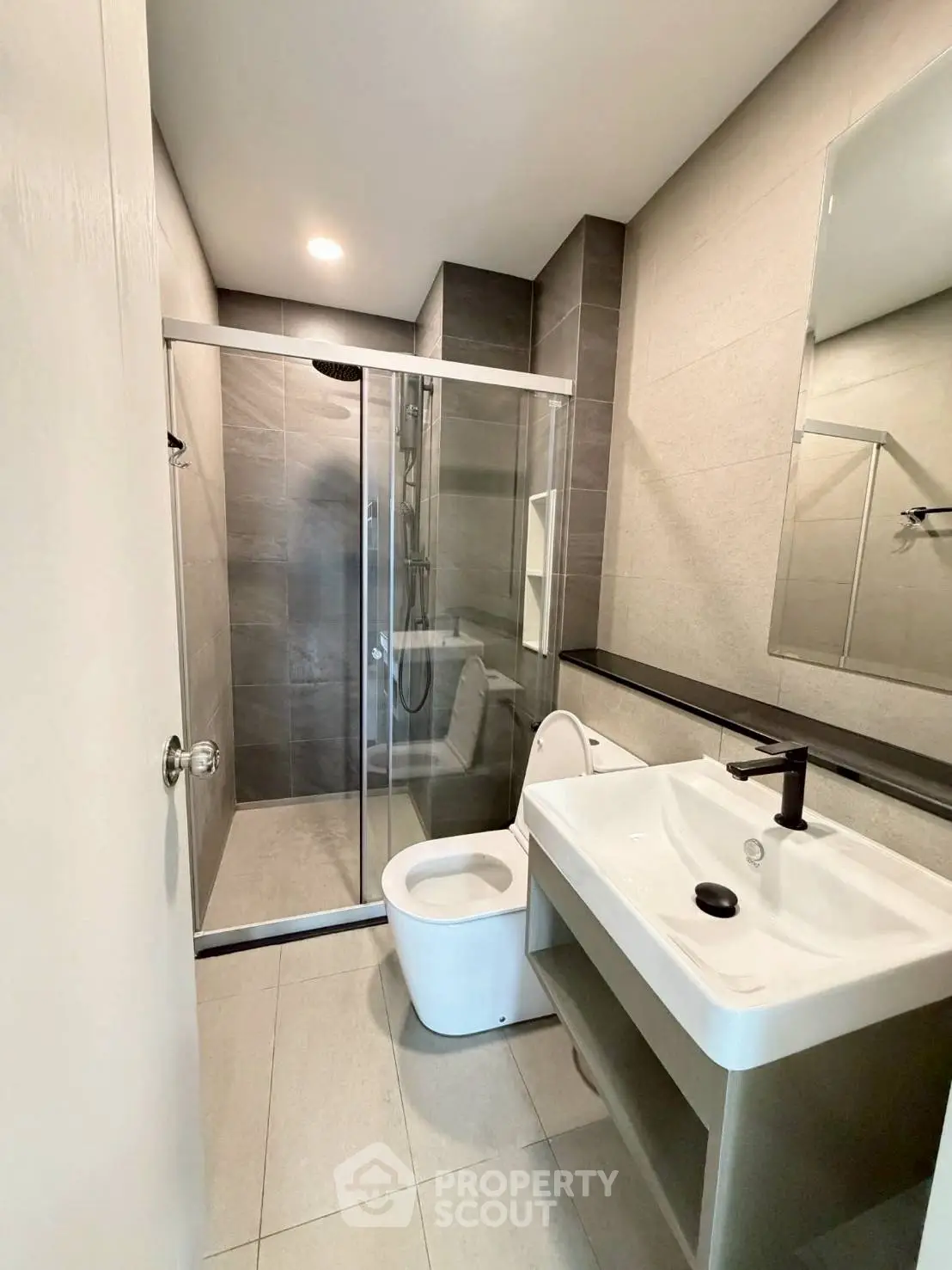 Modern bathroom with sleek design, featuring a glass shower enclosure and contemporary fixtures.