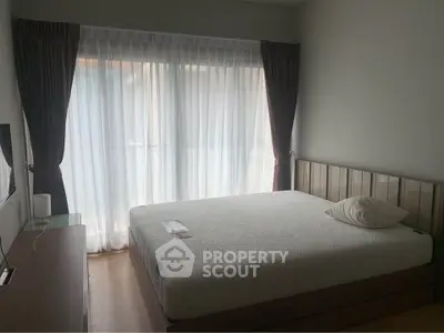 Spacious bedroom with large window and modern furnishings