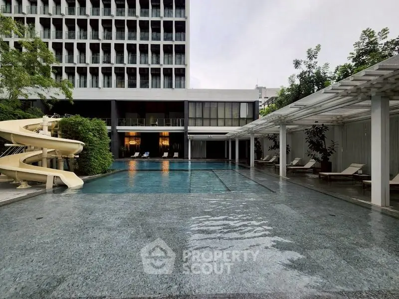 Luxurious residential pool area with slide and modern architecture.